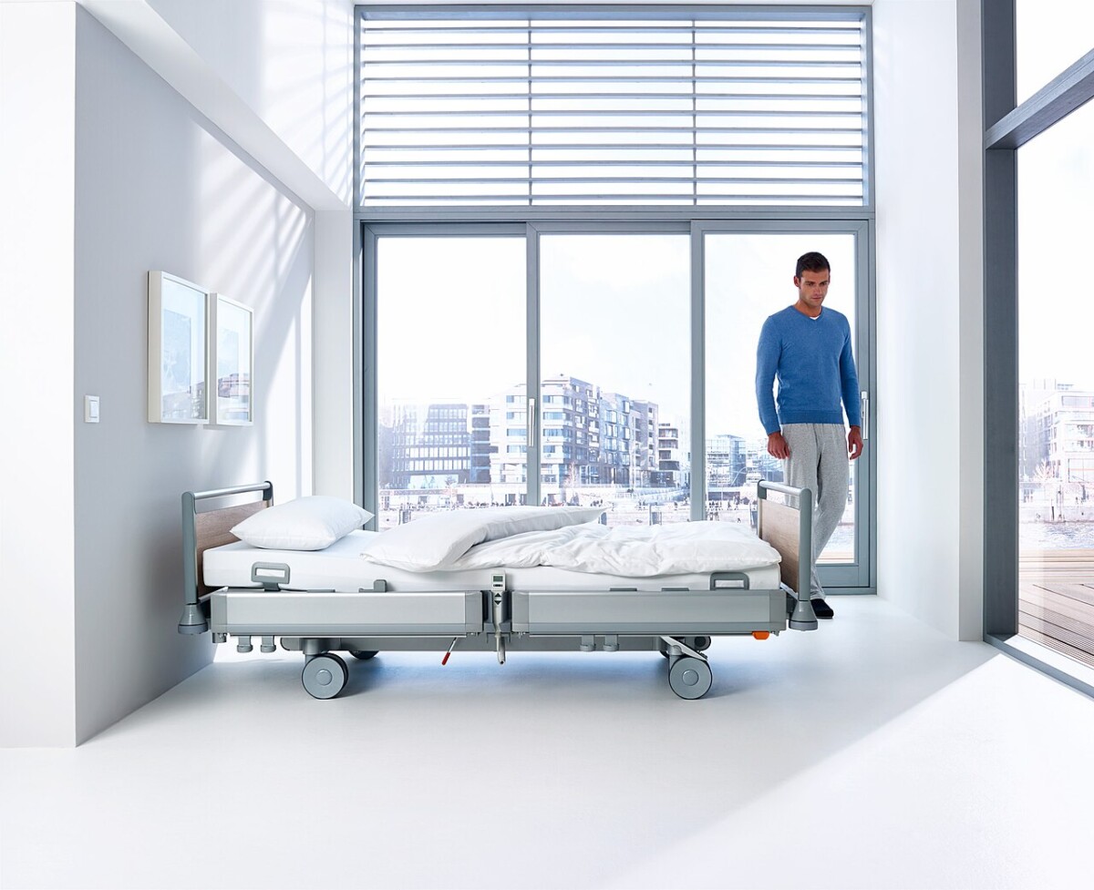 Lit médicalisé électrique à hauteur variable avec panneaux en bois, installé dans une chambre lumineuse