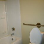 Salle de bain adaptée pour personne âgée avec barre d'appui fixée au mur près des toilettes et de la douche