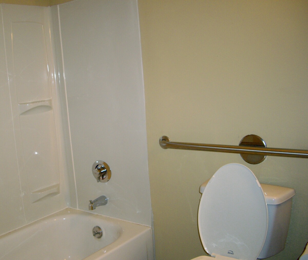 Salle de bain adaptée pour personne âgée avec barre d'appui fixée au mur près des toilettes et de la douche